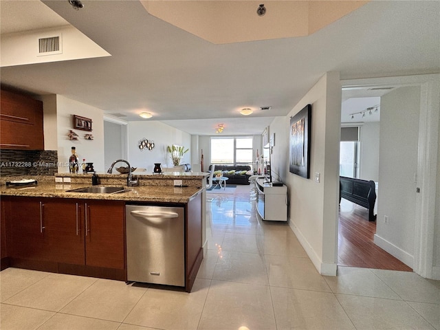 kitchen featuring sink, light tile patterned floors, dishwasher, and stone counters