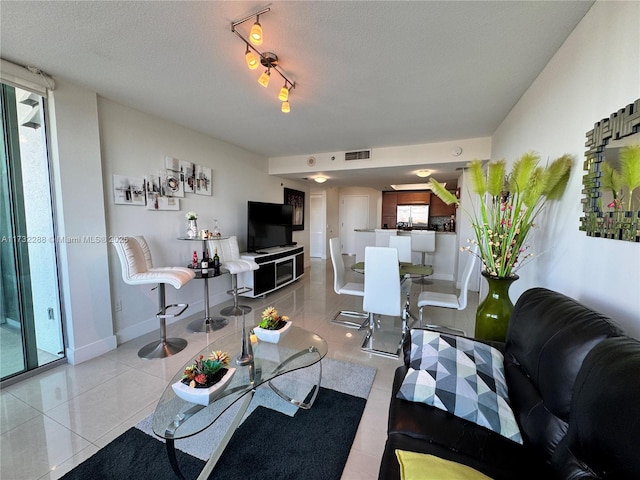 living room featuring light tile patterned floors, track lighting, and a textured ceiling