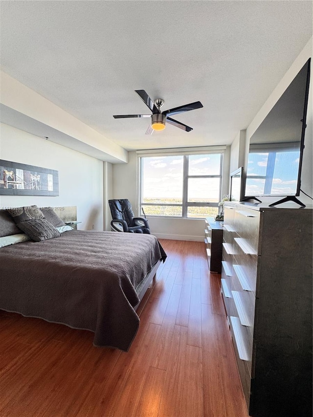 bedroom with a textured ceiling, dark hardwood / wood-style floors, and ceiling fan