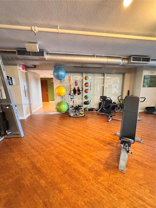 exercise room with carpet floors and a textured ceiling