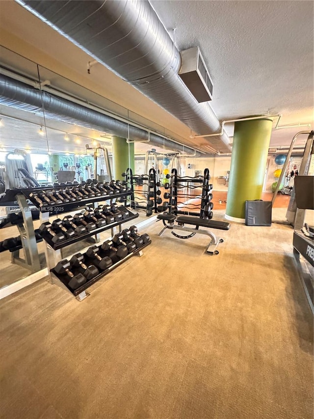 gym featuring a textured ceiling and carpet