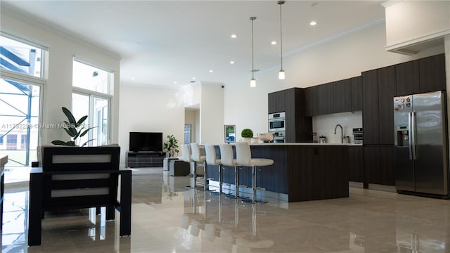 kitchen featuring hanging light fixtures, a center island, dark brown cabinetry, stainless steel fridge with ice dispenser, and crown molding