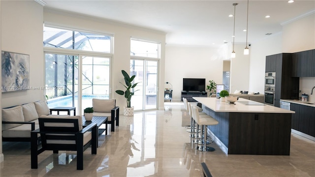 kitchen with pendant lighting, crown molding, a kitchen breakfast bar, a center island, and a high ceiling