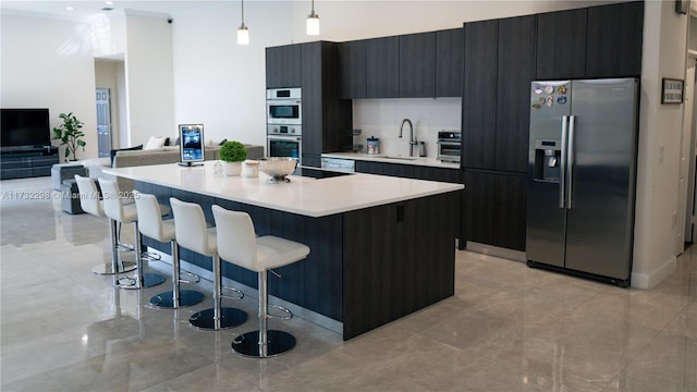 kitchen with pendant lighting, sink, a breakfast bar area, appliances with stainless steel finishes, and a kitchen island with sink