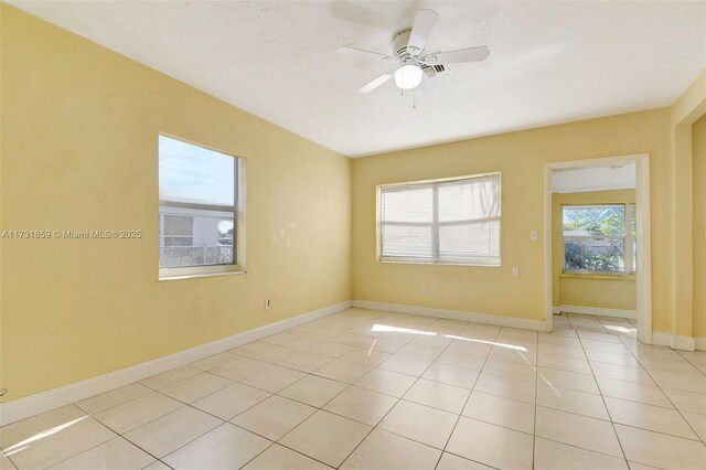 tiled empty room with ceiling fan with notable chandelier