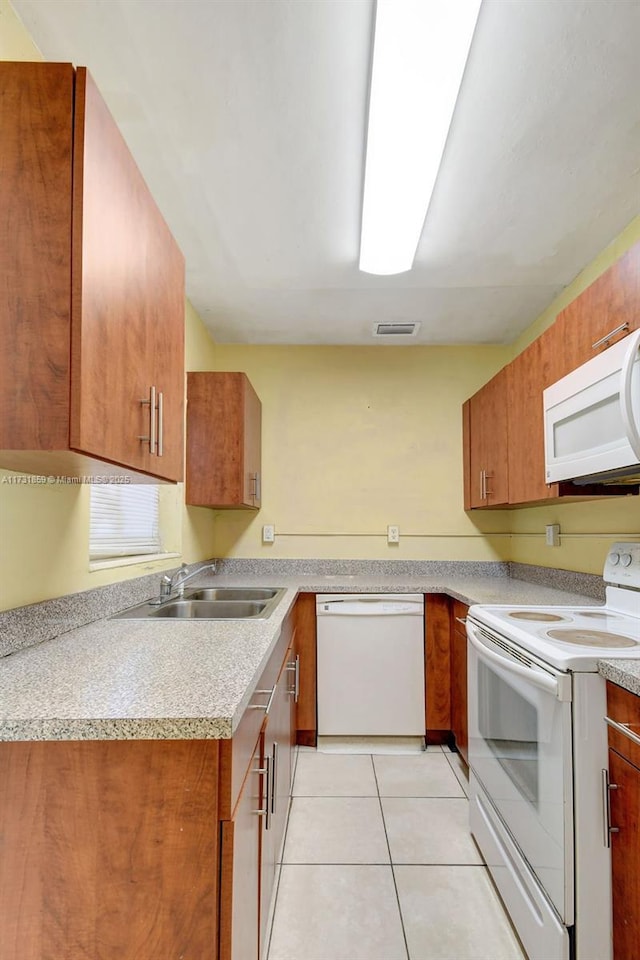 kitchen featuring white appliances, sink, and light tile patterned floors