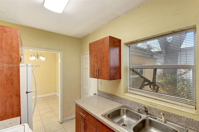 kitchen with sink, light tile patterned floors, hanging light fixtures, and white refrigerator