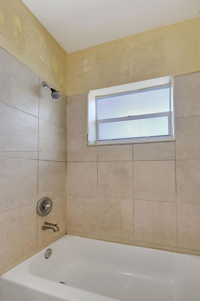 bathroom featuring tiled shower / bath, tile patterned floors, and toilet