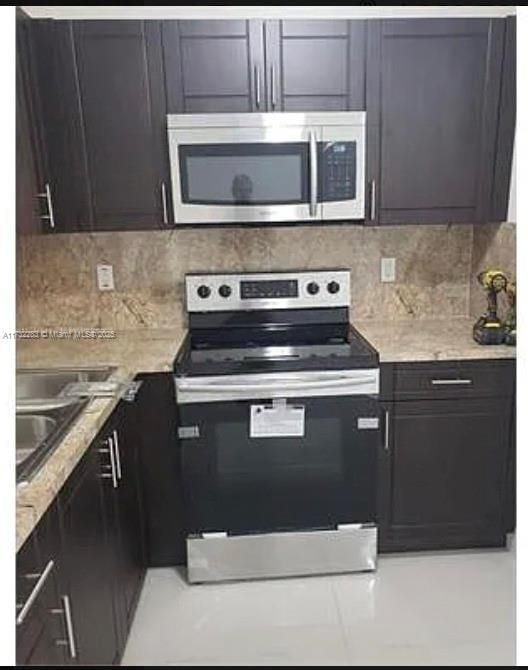 kitchen featuring light stone countertops, appliances with stainless steel finishes, backsplash, and dark brown cabinetry