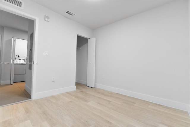 2555 NE 193rd St Unit 2102, Miami, FL 33180 - unfurnished bedroom with washing machine and dryer, a walk in closet, light hardwood / wood-style floors, and a closet