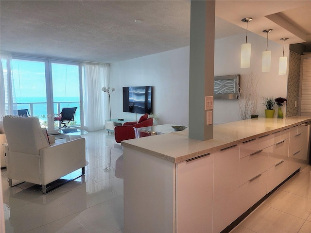 kitchen with white cabinets, decorative light fixtures, a wall of windows, and light tile patterned floors