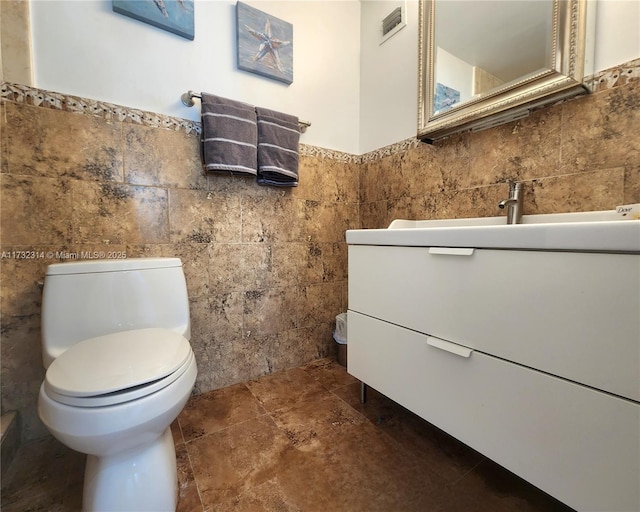 bathroom with tile walls, vanity, and toilet