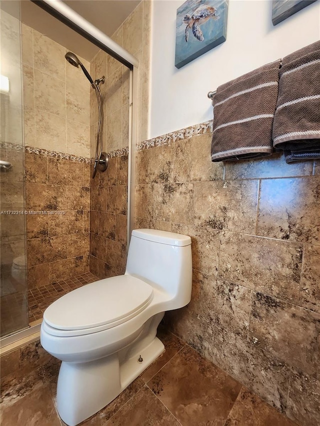 bathroom with tiled shower, toilet, and tile walls