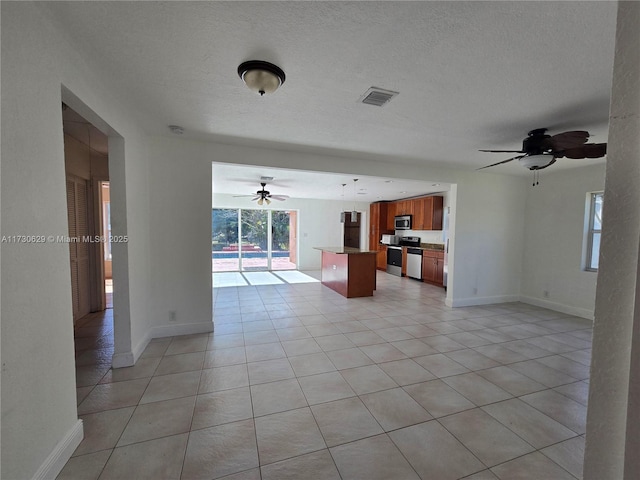 unfurnished living room featuring light tile patterned flooring, ceiling fan, and a textured ceiling