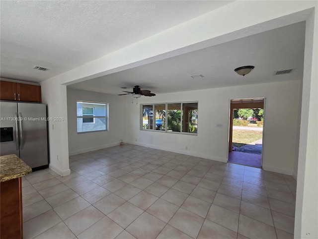 interior space with light tile patterned floors, a textured ceiling, and ceiling fan