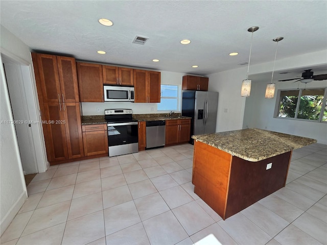 kitchen featuring sink, decorative light fixtures, a center island, dark stone countertops, and stainless steel appliances