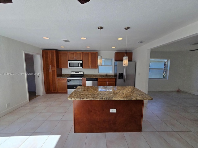 kitchen with pendant lighting, sink, light tile patterned floors, dark stone countertops, and stainless steel appliances