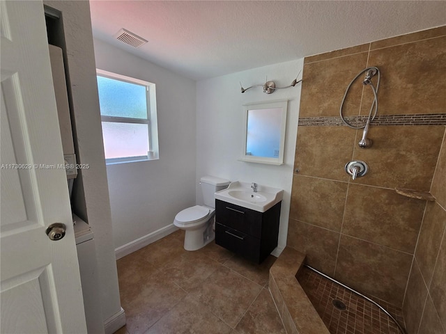 bathroom with tiled shower, tile patterned floors, toilet, a textured ceiling, and vanity