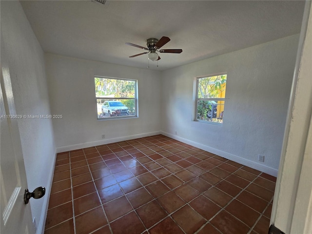 tiled empty room featuring plenty of natural light and ceiling fan