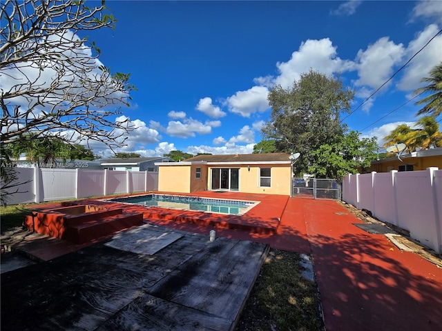 rear view of property with a fenced in pool and a patio