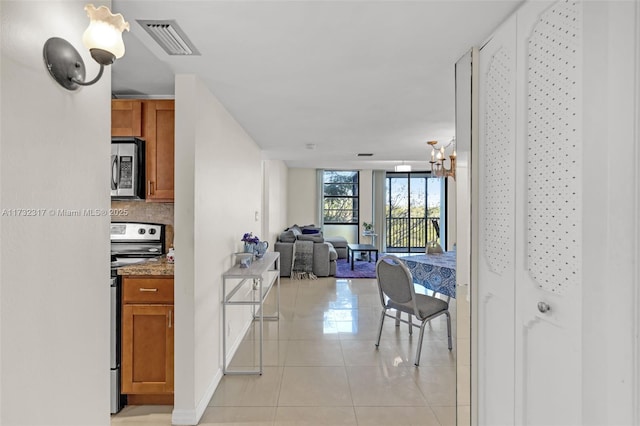 kitchen featuring appliances with stainless steel finishes, light tile patterned floors, and light stone counters