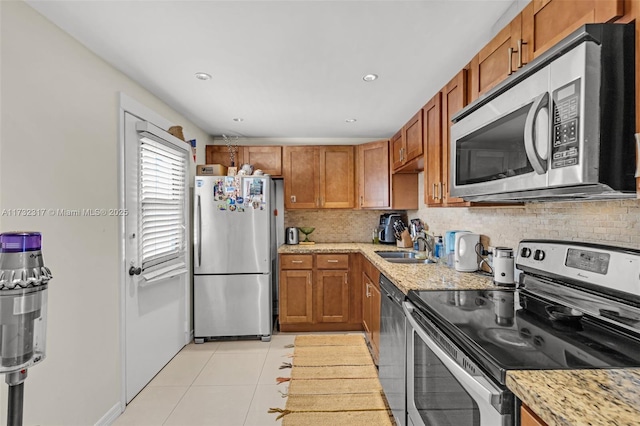 kitchen with light stone countertops, appliances with stainless steel finishes, sink, and light tile patterned floors