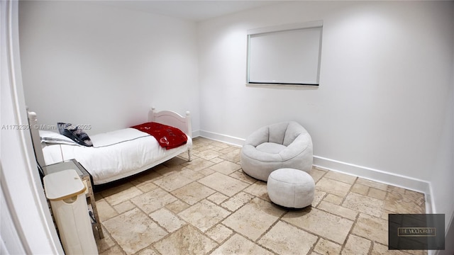 bedroom featuring stone tile floors and baseboards