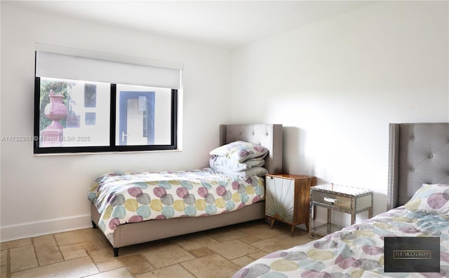 bedroom featuring baseboards and stone tile flooring