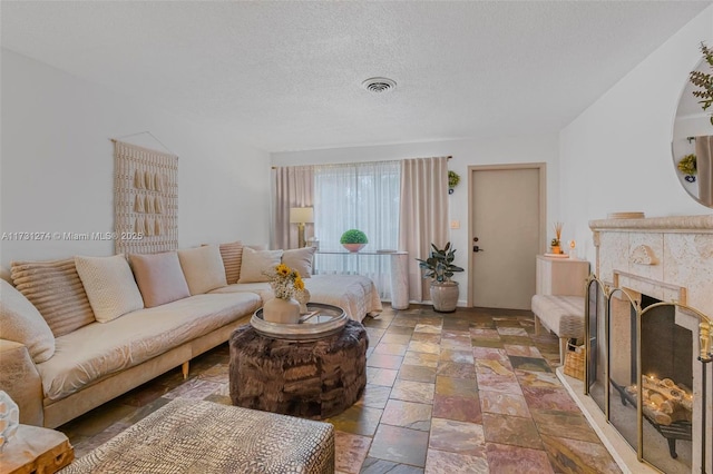 living room with a tiled fireplace and a textured ceiling