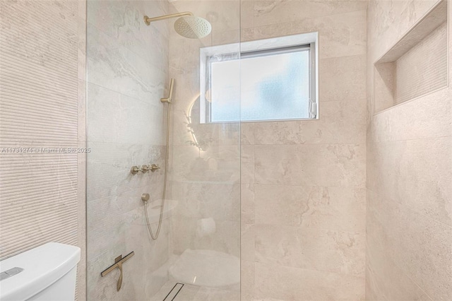 bathroom featuring tiled shower and toilet