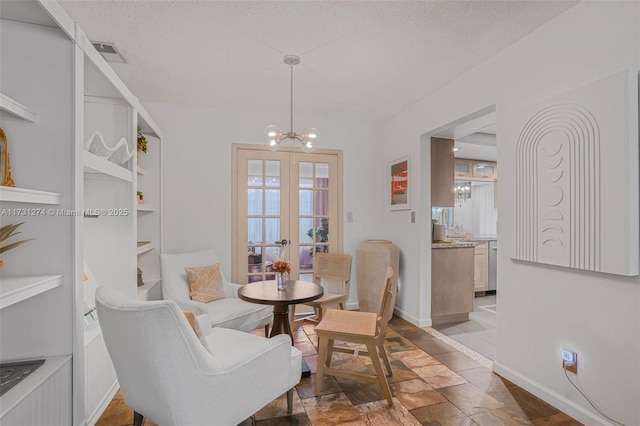 dining area with built in shelves, french doors, a textured ceiling, and a notable chandelier