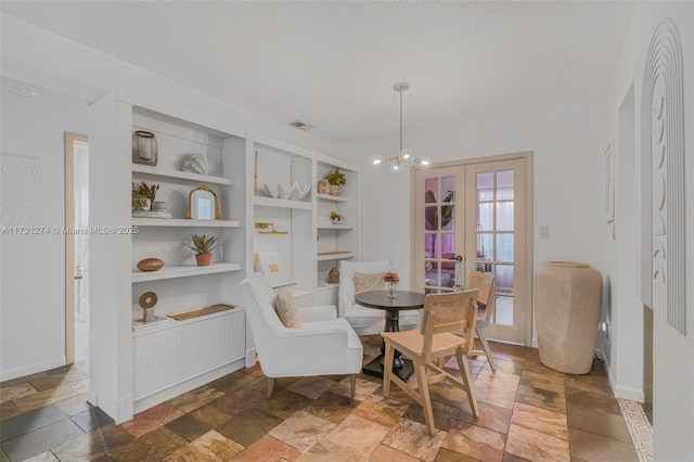 dining room featuring a notable chandelier, a textured ceiling, and built in shelves