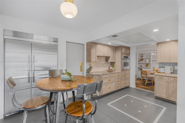 kitchen featuring light brown cabinetry, dark tile patterned flooring, and appliances with stainless steel finishes