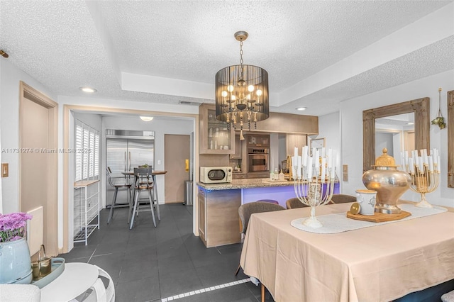 dining room featuring a notable chandelier, a raised ceiling, and a textured ceiling