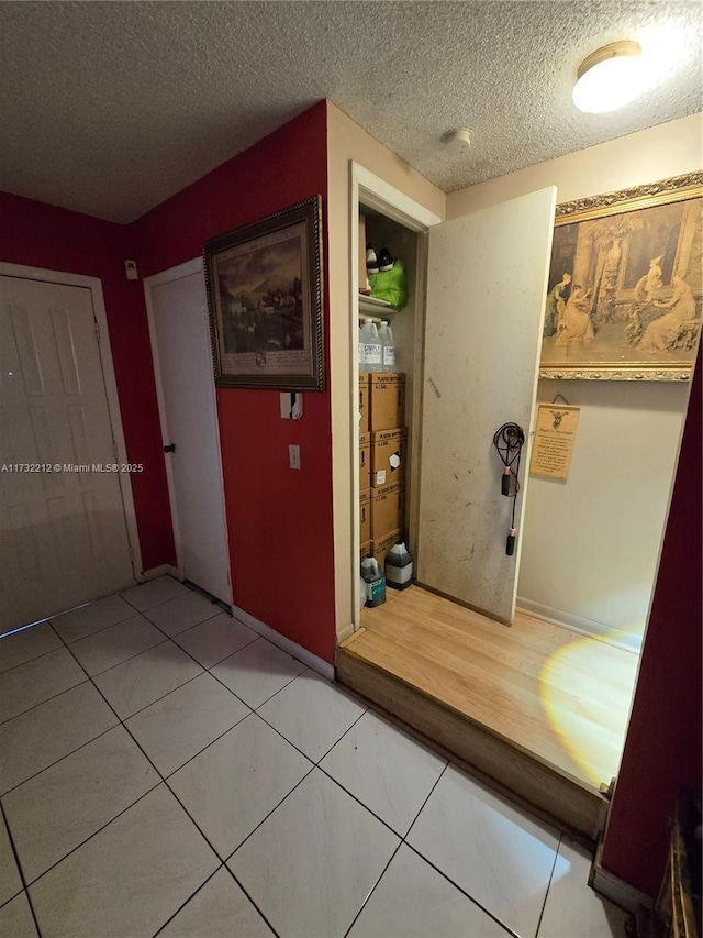 hallway featuring tile patterned floors and a textured ceiling