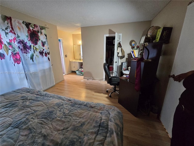 bedroom featuring ensuite bath, light hardwood / wood-style floors, a closet, and a textured ceiling