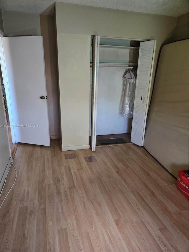 unfurnished bedroom with a closet, a textured ceiling, and light wood-type flooring