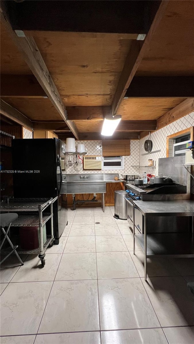 kitchen with black fridge, high end stainless steel range, beam ceiling, and decorative backsplash