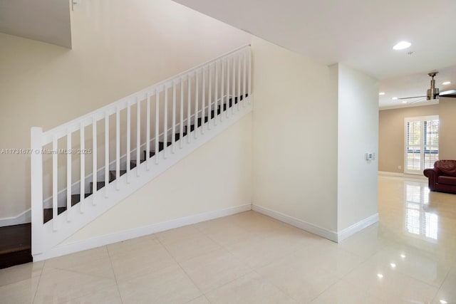 stairway featuring tile patterned floors and ceiling fan