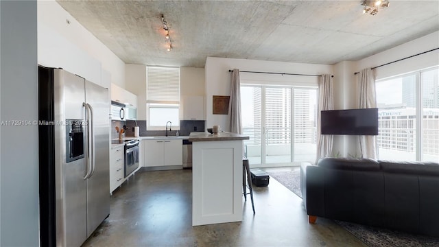 kitchen featuring sink, white cabinetry, concrete floors, appliances with stainless steel finishes, and backsplash