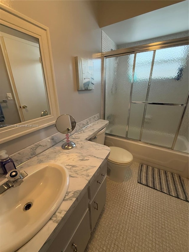 bathroom featuring toilet, tile patterned flooring, bath / shower combo with glass door, and vanity