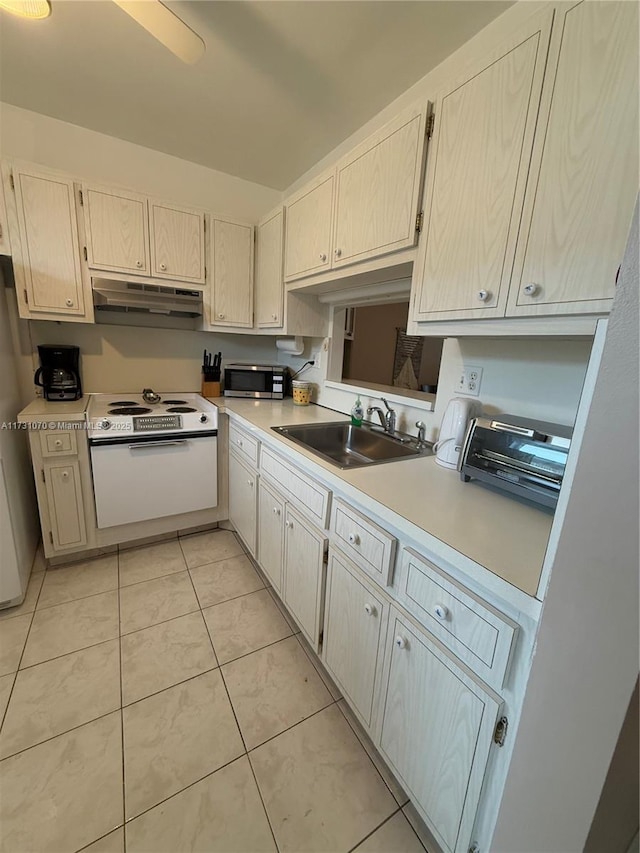 kitchen featuring light tile patterned floors, under cabinet range hood, a sink, light countertops, and appliances with stainless steel finishes