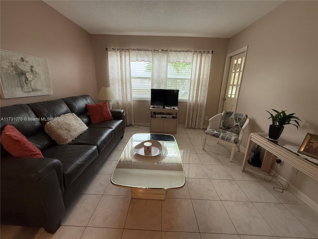 living room with a textured ceiling, baseboards, and light tile patterned floors