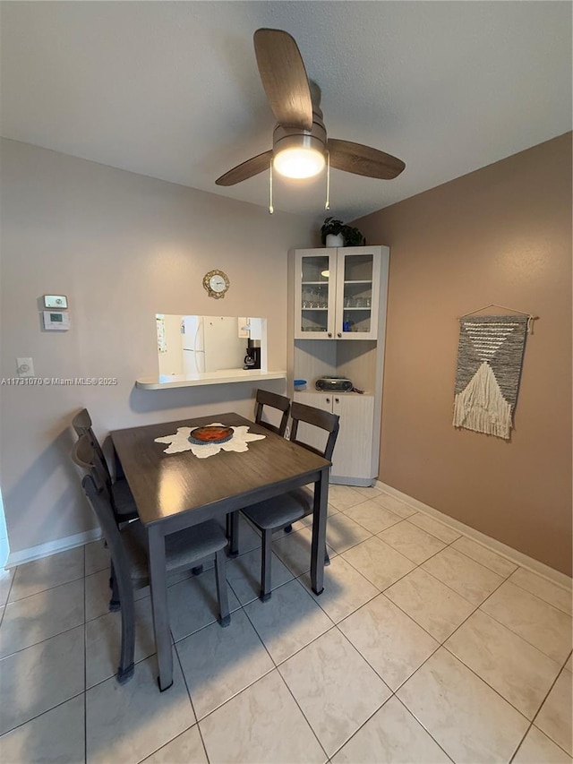 dining space featuring baseboards, a ceiling fan, and light tile patterned flooring