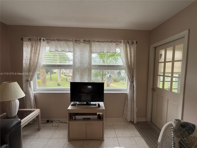 interior space featuring light tile patterned floors, a textured ceiling, baseboards, and a wealth of natural light