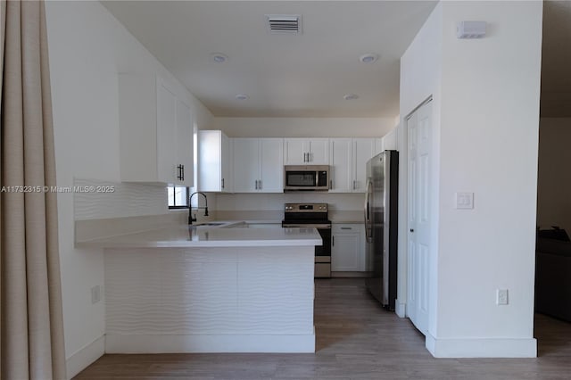 kitchen featuring tasteful backsplash, white cabinetry, sink, kitchen peninsula, and stainless steel appliances