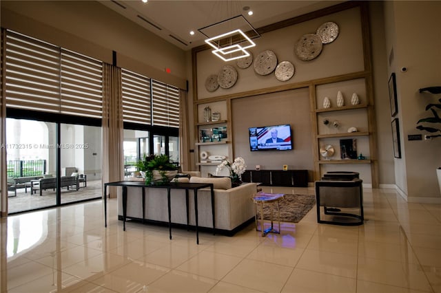 living room with light tile patterned flooring, a towering ceiling, a notable chandelier, and built in features