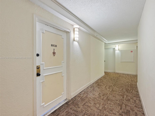 corridor featuring a textured ceiling and carpet flooring