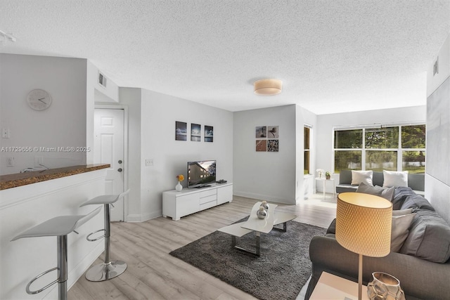 living room featuring a textured ceiling and light wood-type flooring