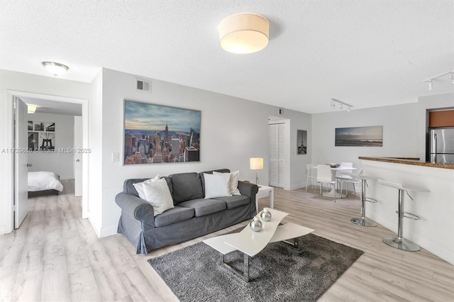 living room with light hardwood / wood-style flooring, a textured ceiling, and track lighting